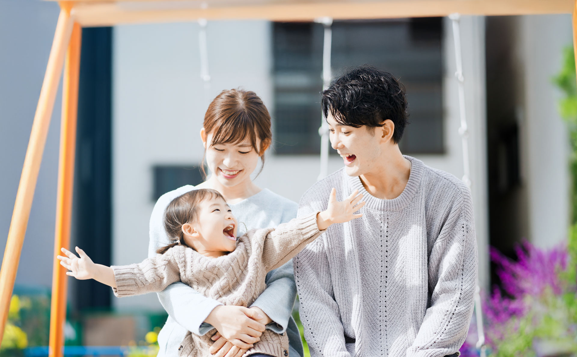 未就学児の女の子と両親が笑い合う写真